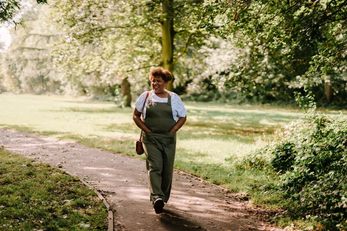 A woman enjoying a gentle walk along a sunlit park path