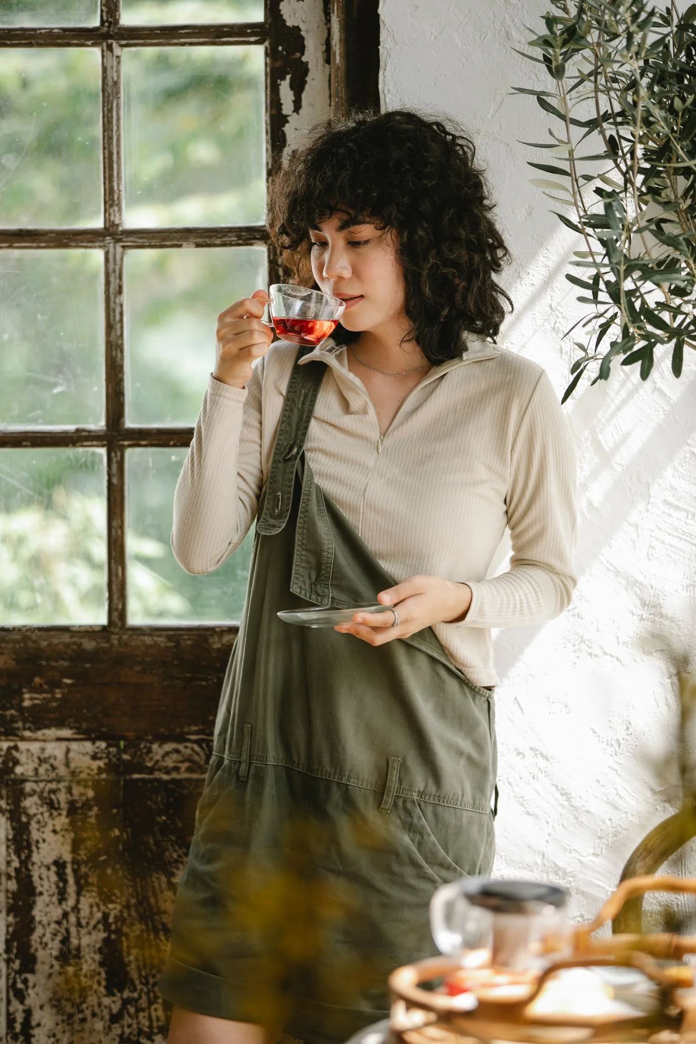 一位女性在质朴窗边捧着一杯茶稍作休息