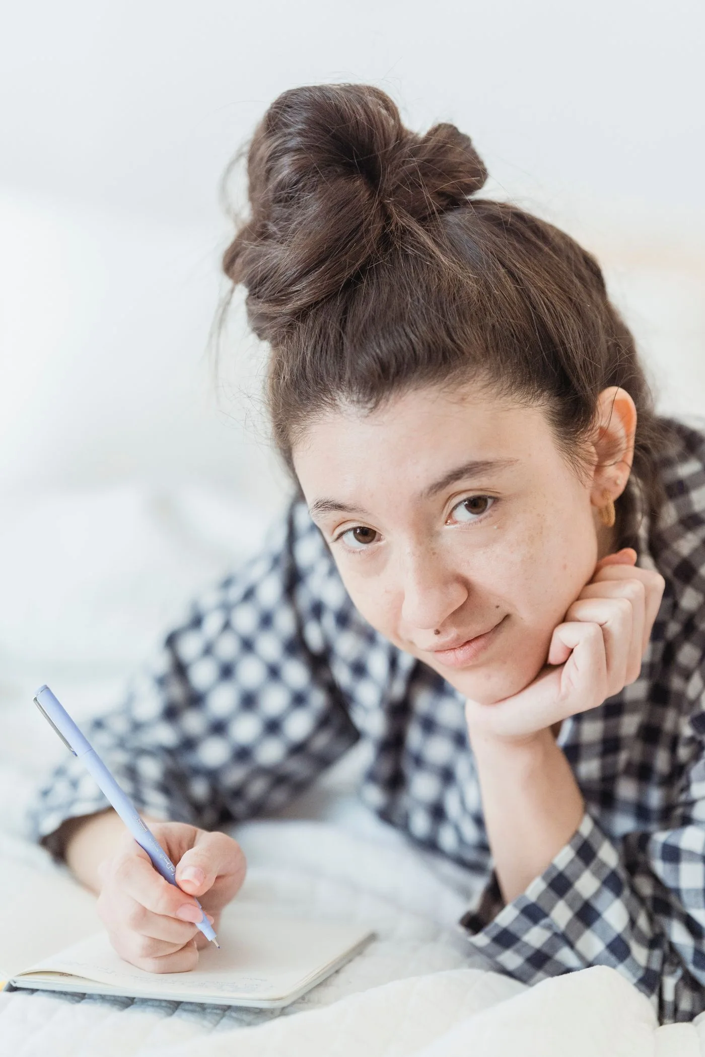 A woman relaxing in bed with a notebook and pen